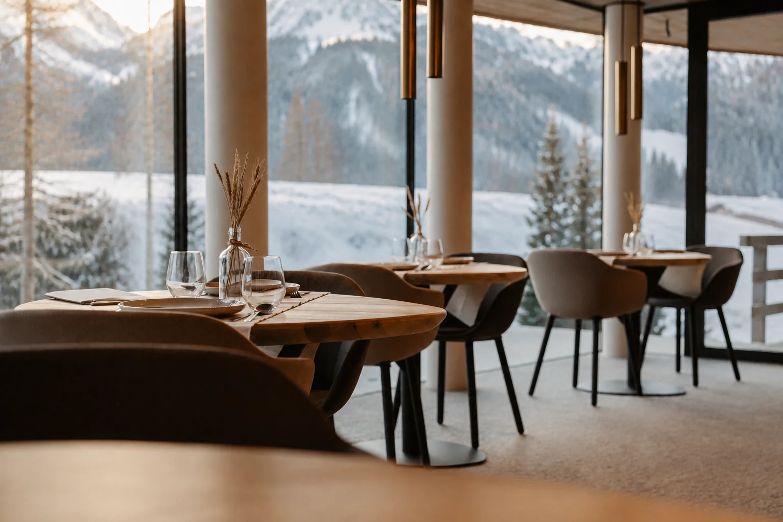 Sala colazione con tavoli in legno e vetrate sul paesaggio innevato