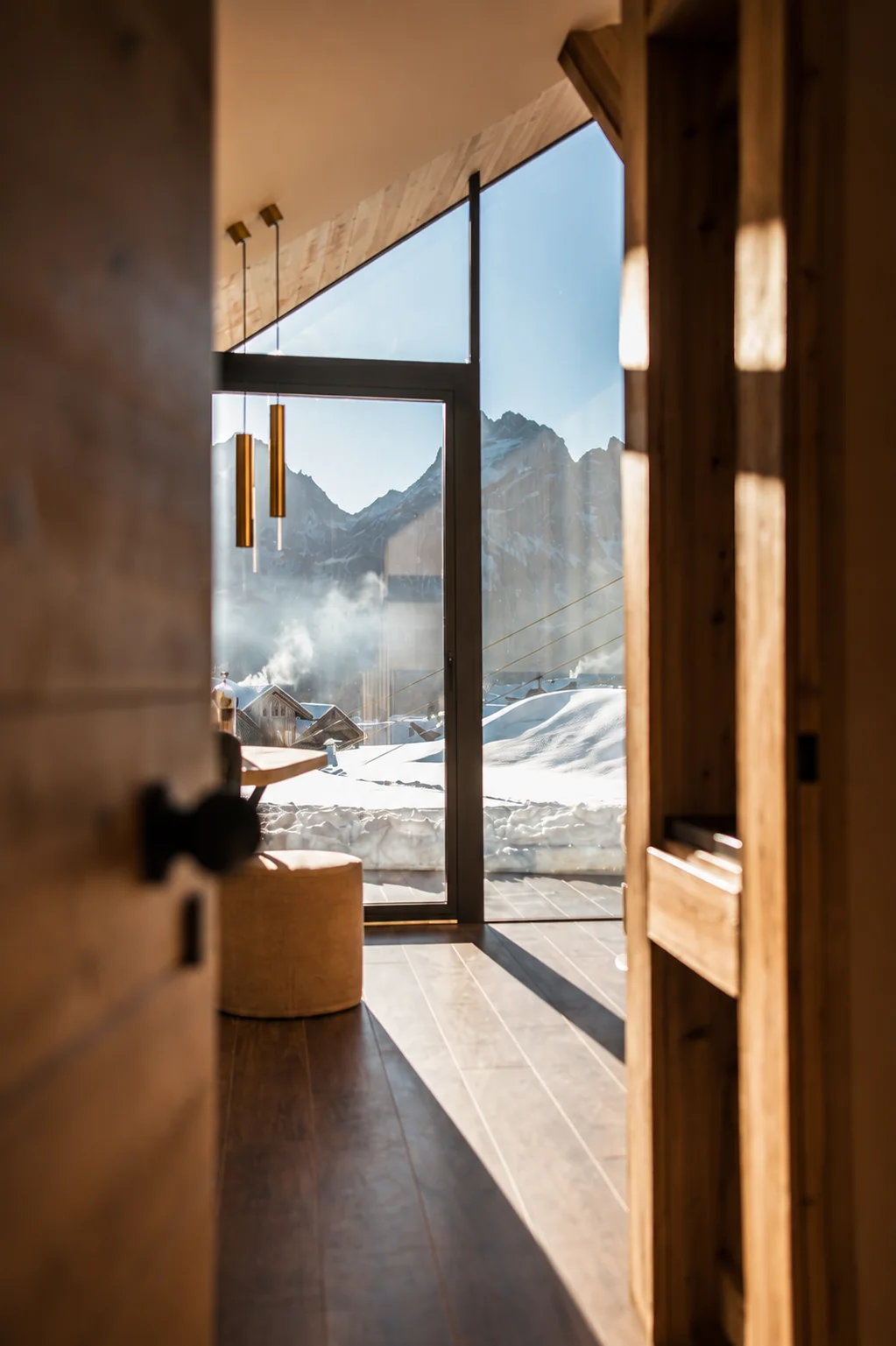 Vista dalla porta del lodge verso la grande vetrata e le Dolomiti innevate