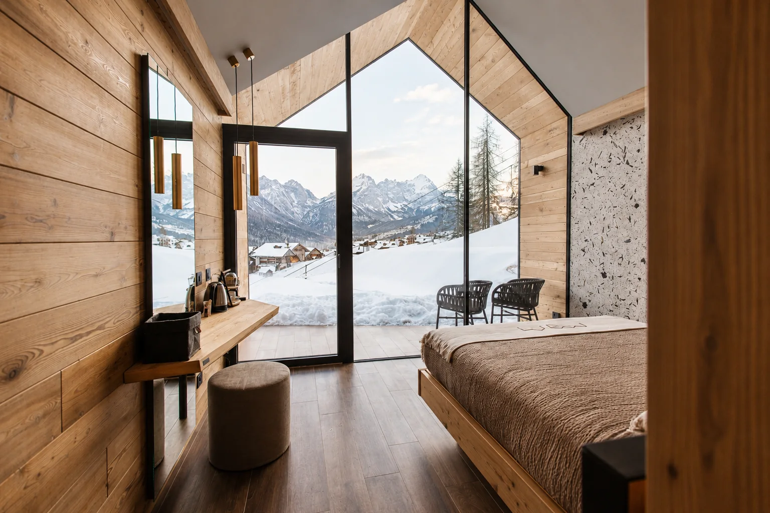 Interno del lodge in legno con letto e vetrata panoramica sulle montagne